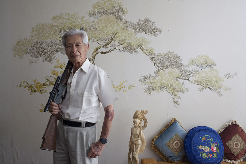 Miguel Situ Rojas holding a hunting rifle at his home
